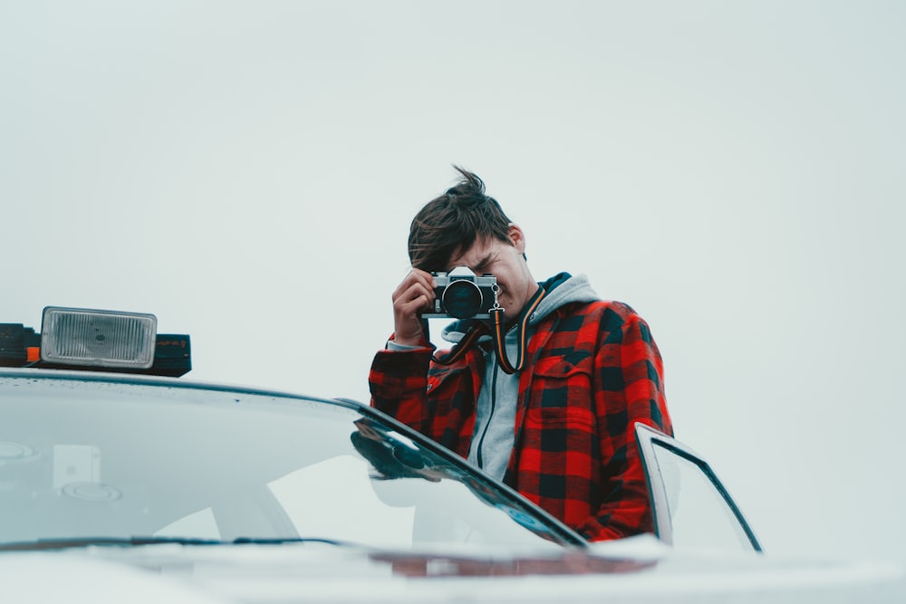 man standing near open door of car using camera