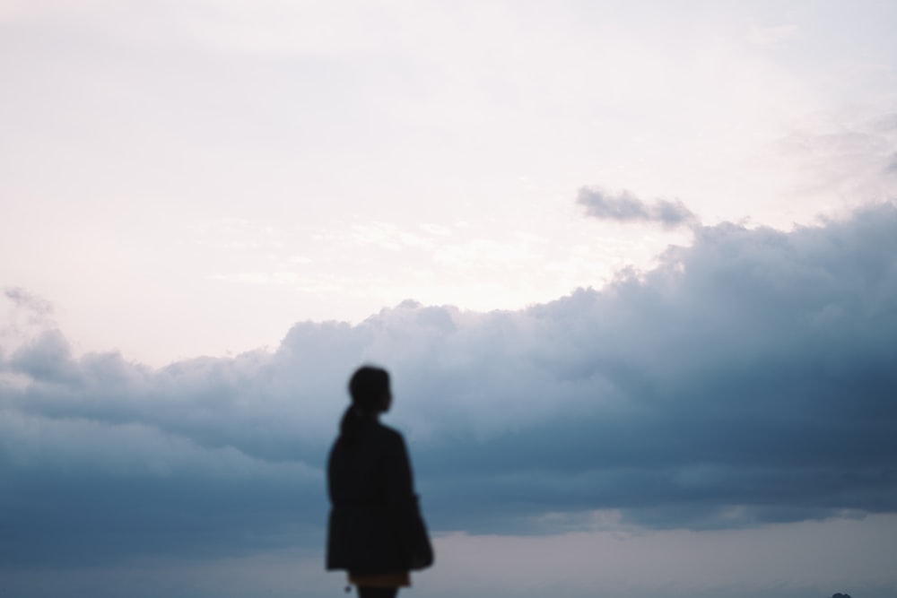 silhouette of woman under gloomy clouds