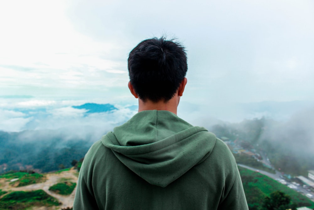 man standing on mountain top with land overview