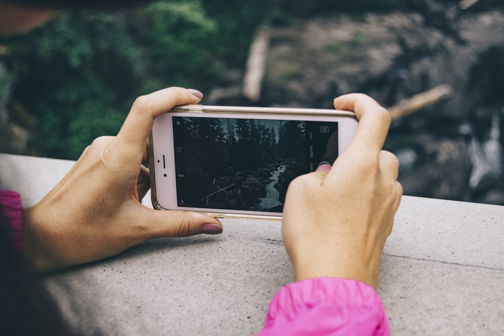 person staking photo of river using iPhone