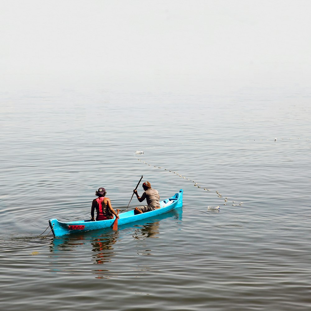 2 person in boat at body of water