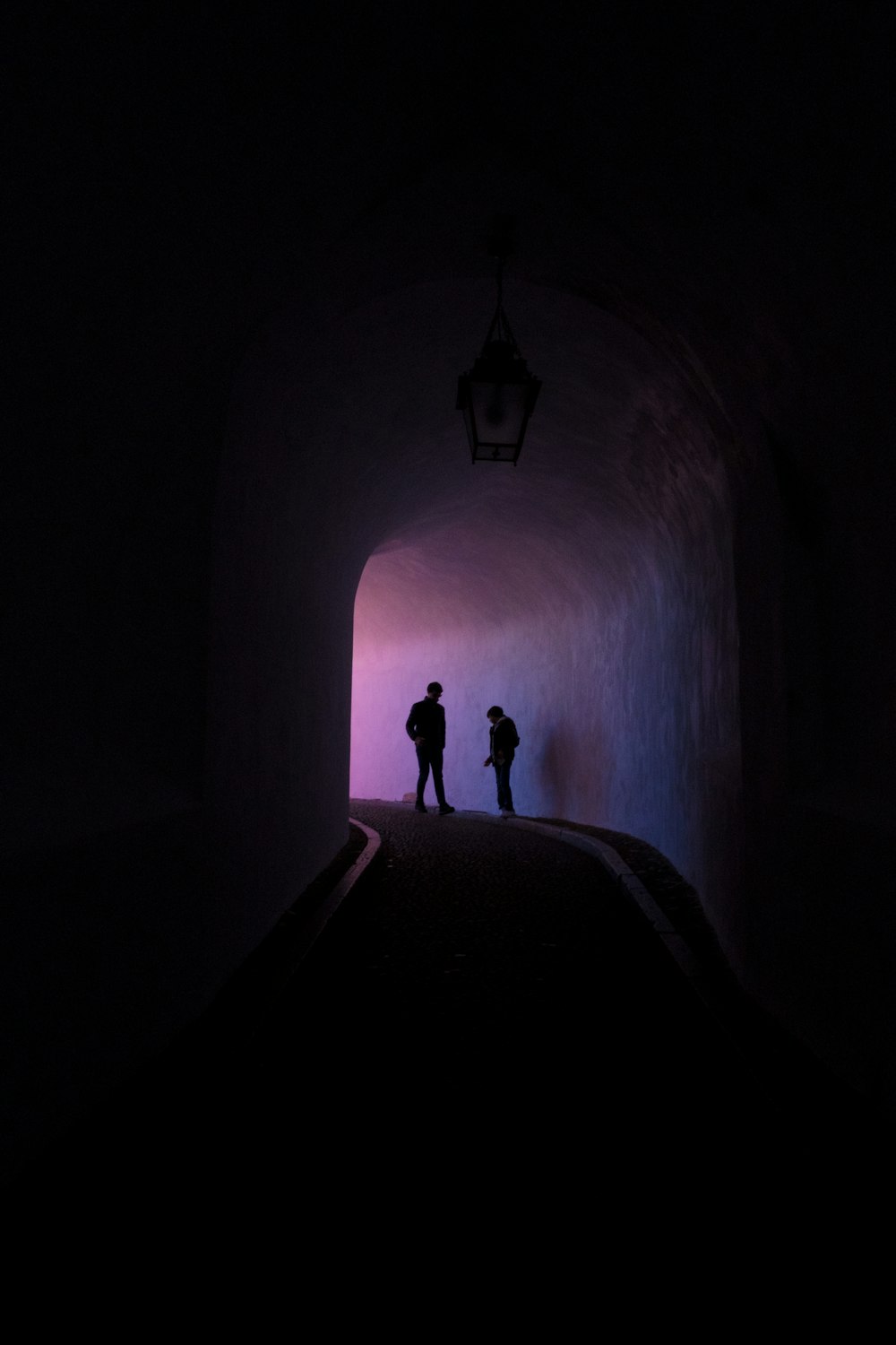 silhouette of two person standing inside tunnel