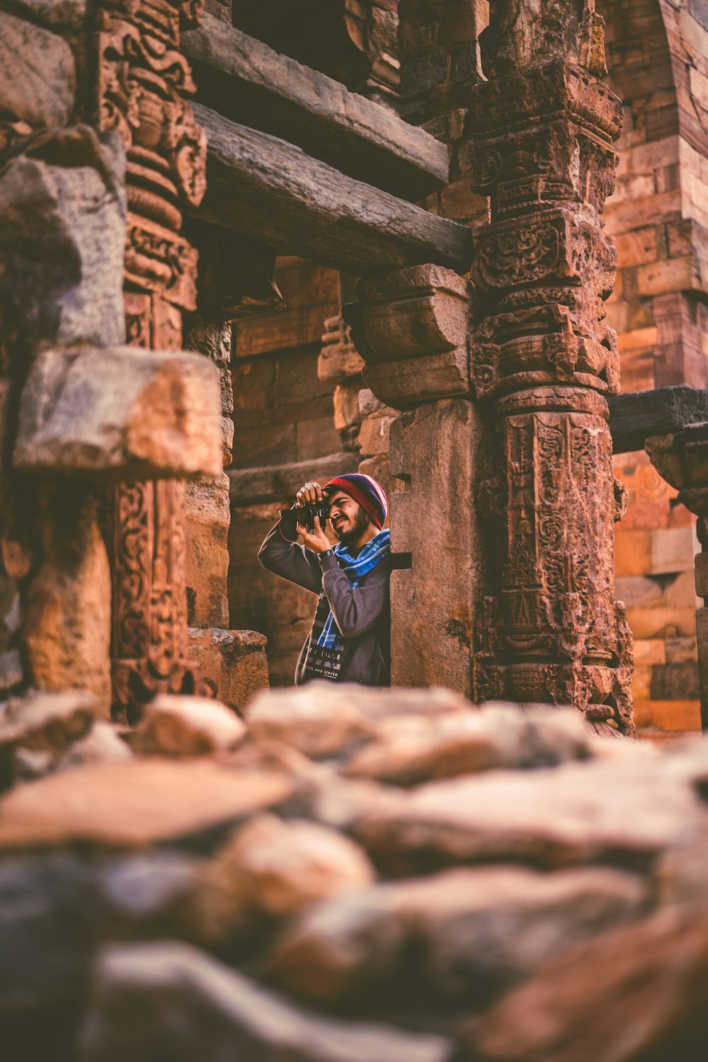 man holding camera leaning on concrete post