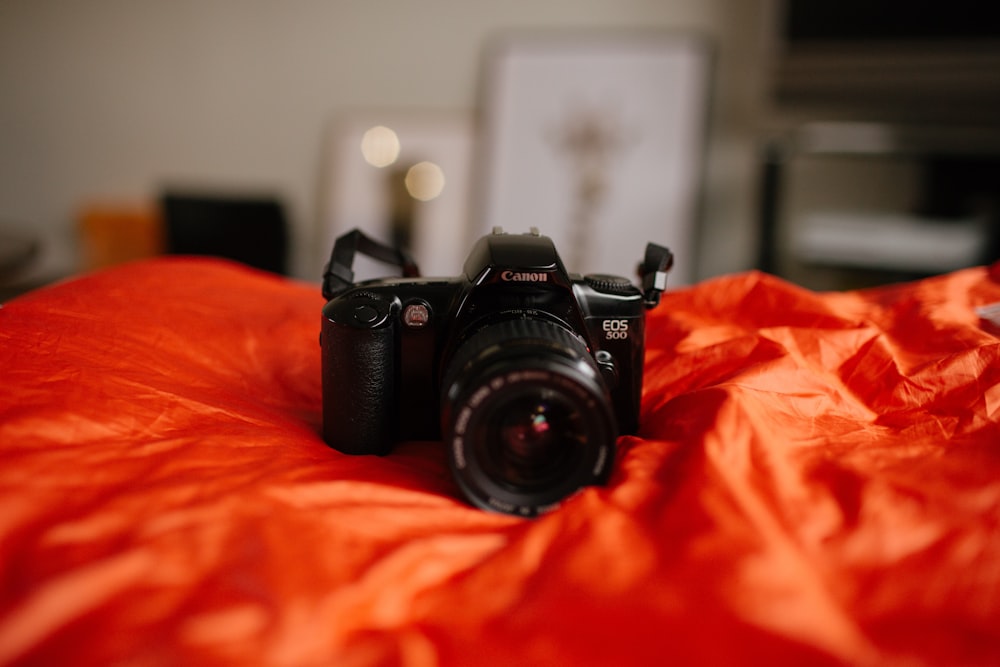 black Canon DSLR camera on red textile