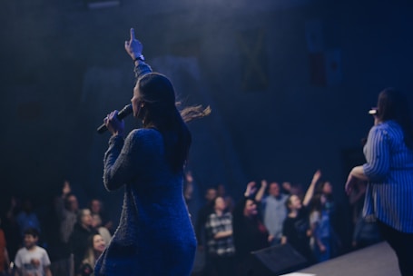 two women singing on stage in front of crowd