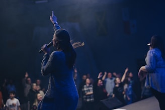 two women singing on stage in front of crowd