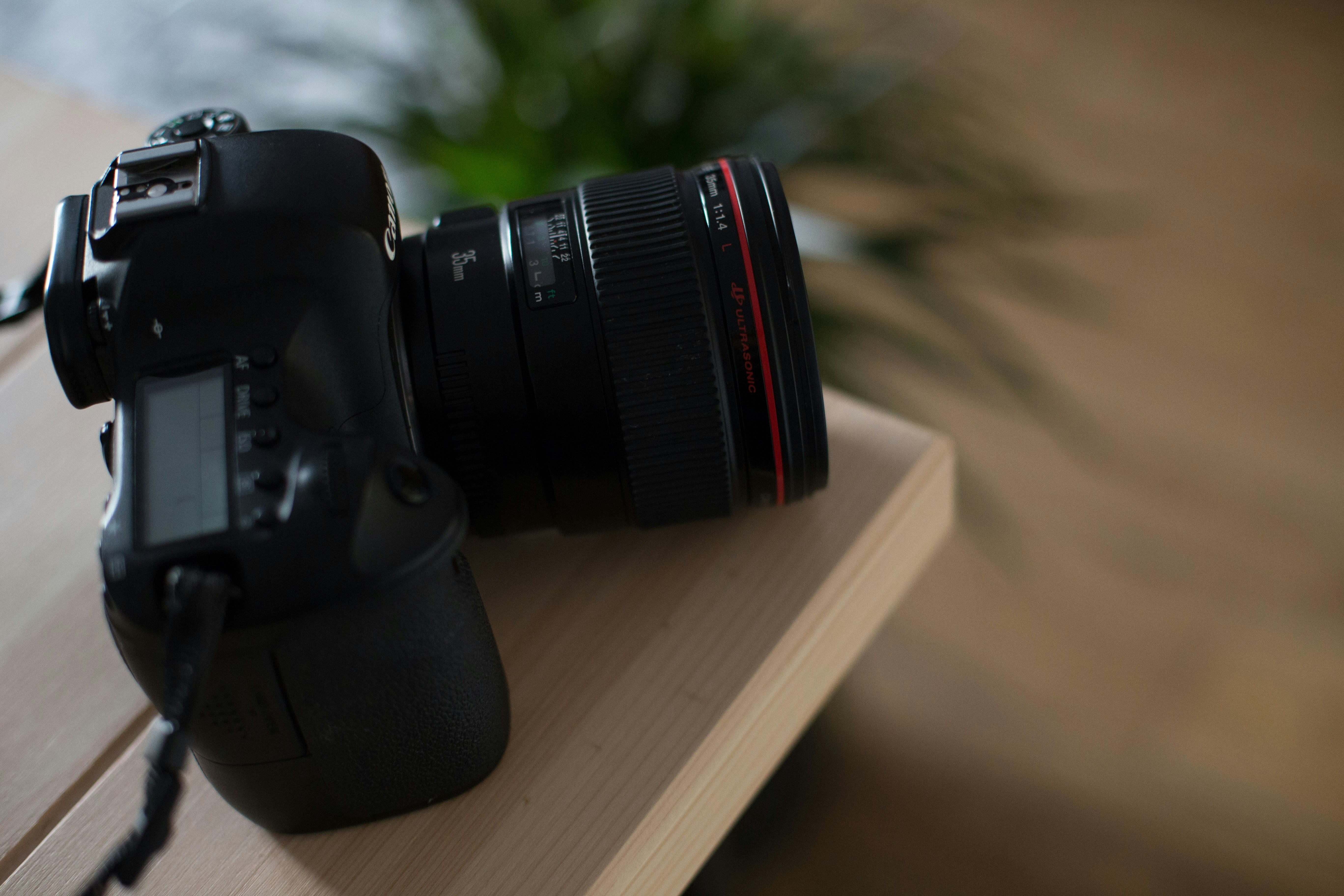 selective focus photography of black DSLR camera on brown wooden table