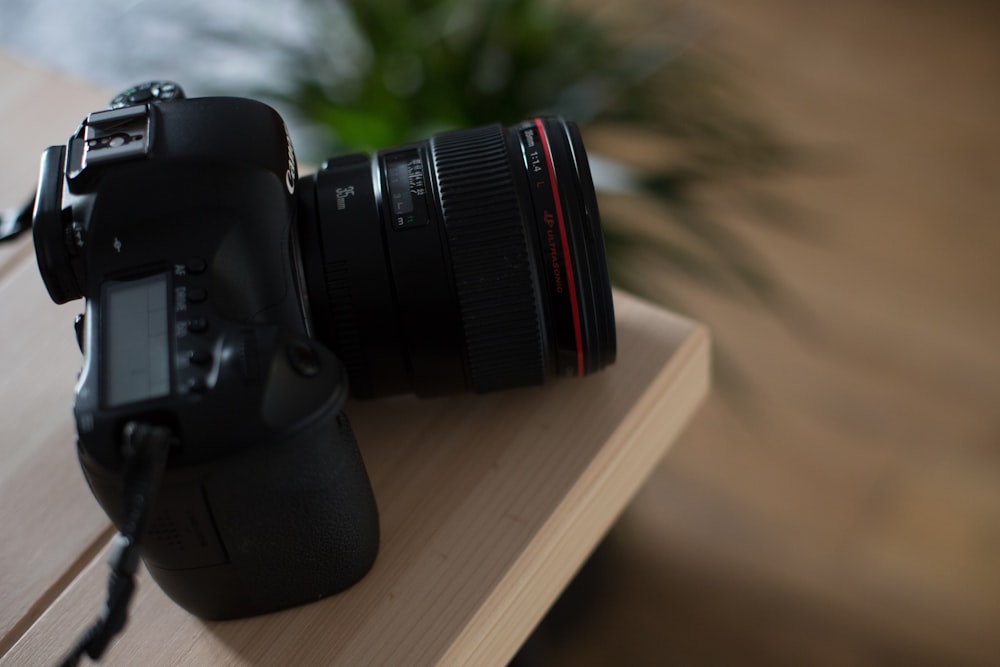 selective focus photography of black DSLR camera on brown wooden table