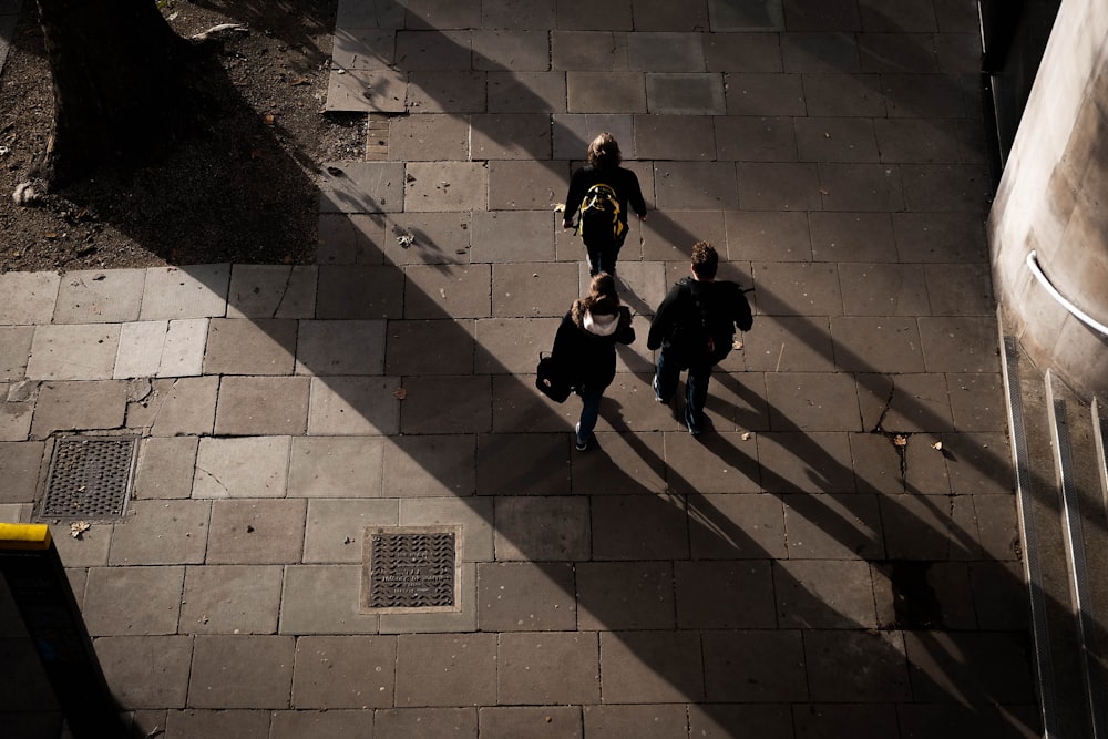 three people walking on concrete pavement