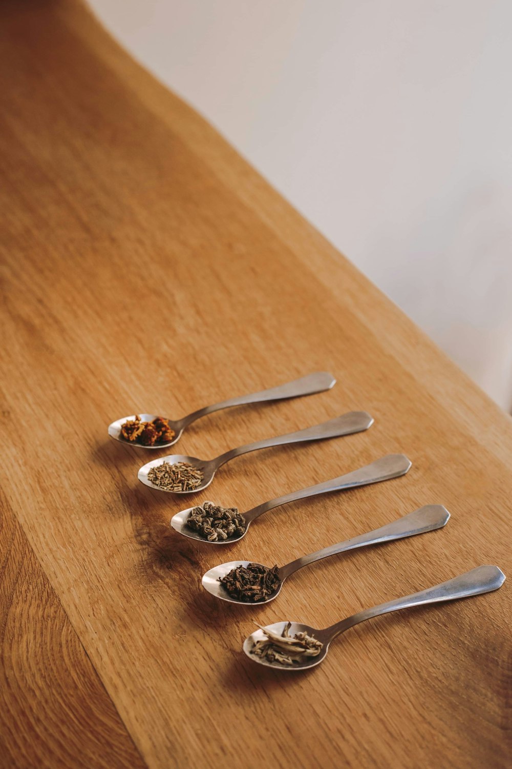 five gray steel spoons on brown wooden table