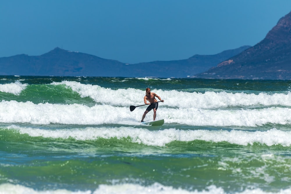 man riding surfboard under blue sky