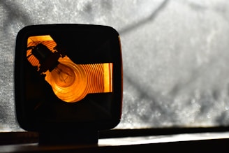 A vibrant orange light bulb glowing amid a dark background, symbolizing bright creative ideas in a tech-driven world.