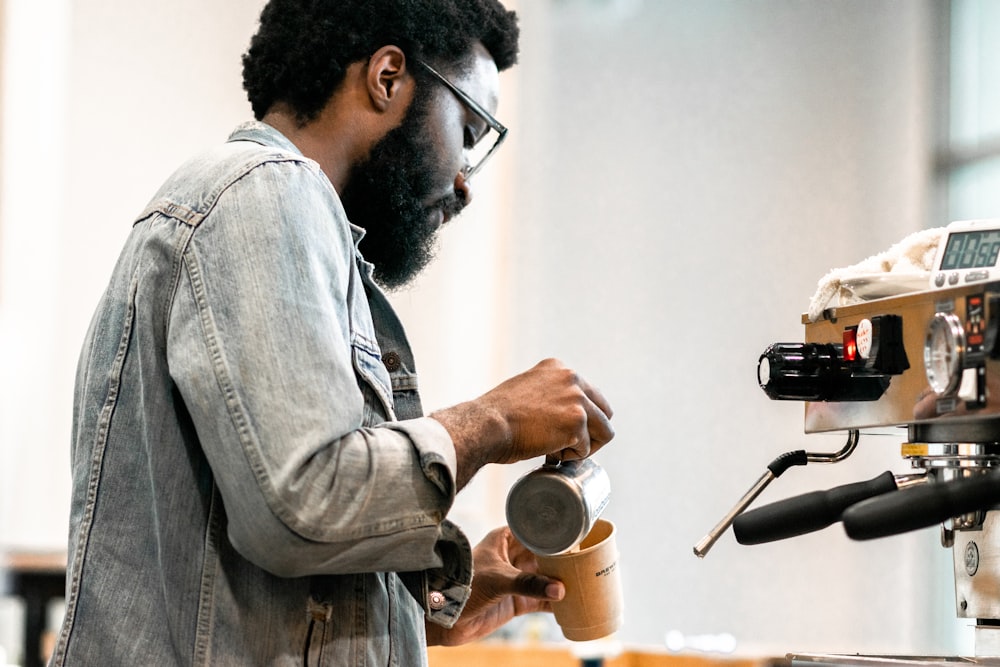 man pouring liquid on mug from can