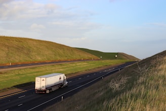 A sturdy mdm transport inc semi-truck cruising along a sunlit highway near Chicago's skyline.