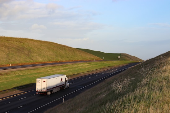 A modern semi-truck driving along a highway with a clear blue sky, symbolizing reliable freight transportation.