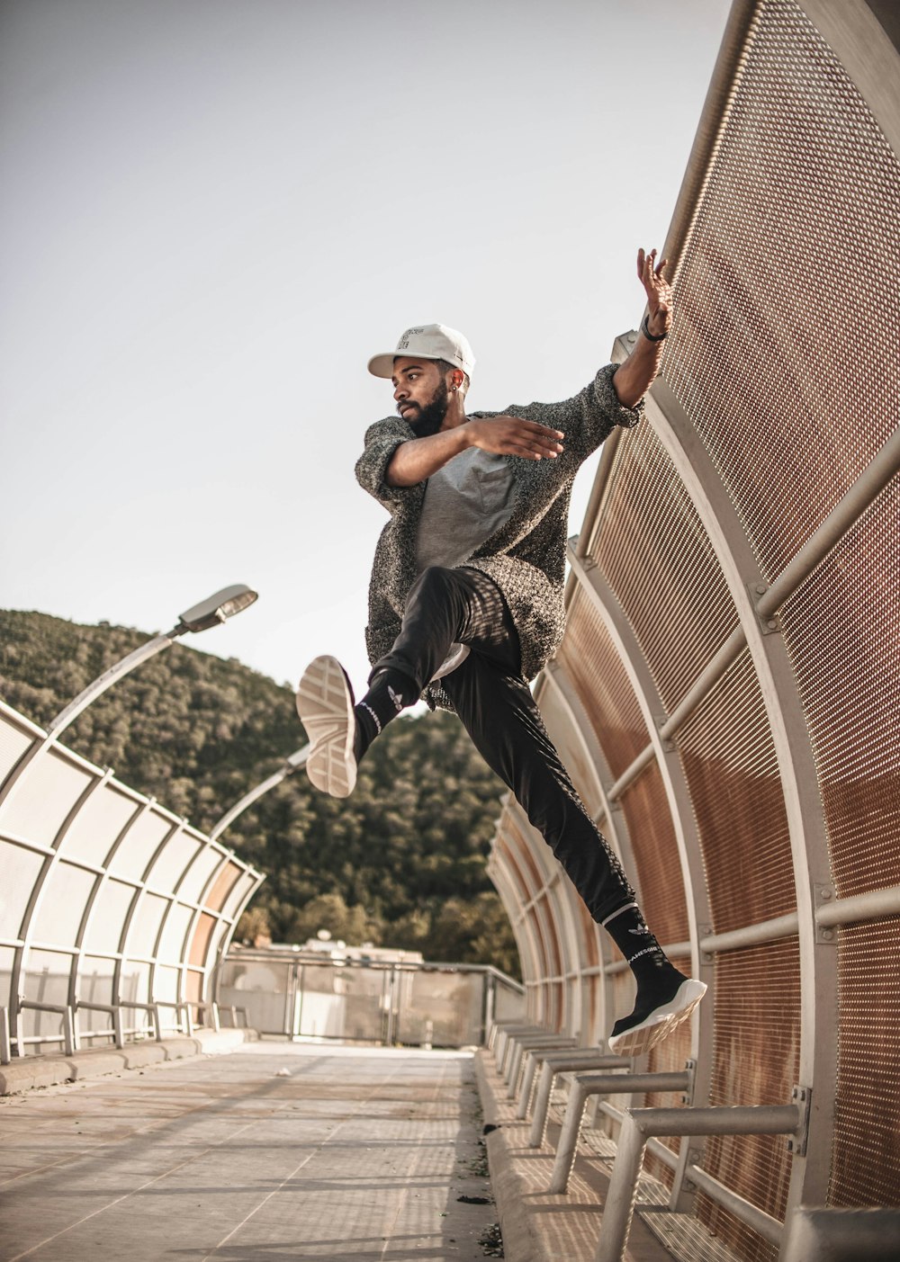 man jumping on gray metal railings