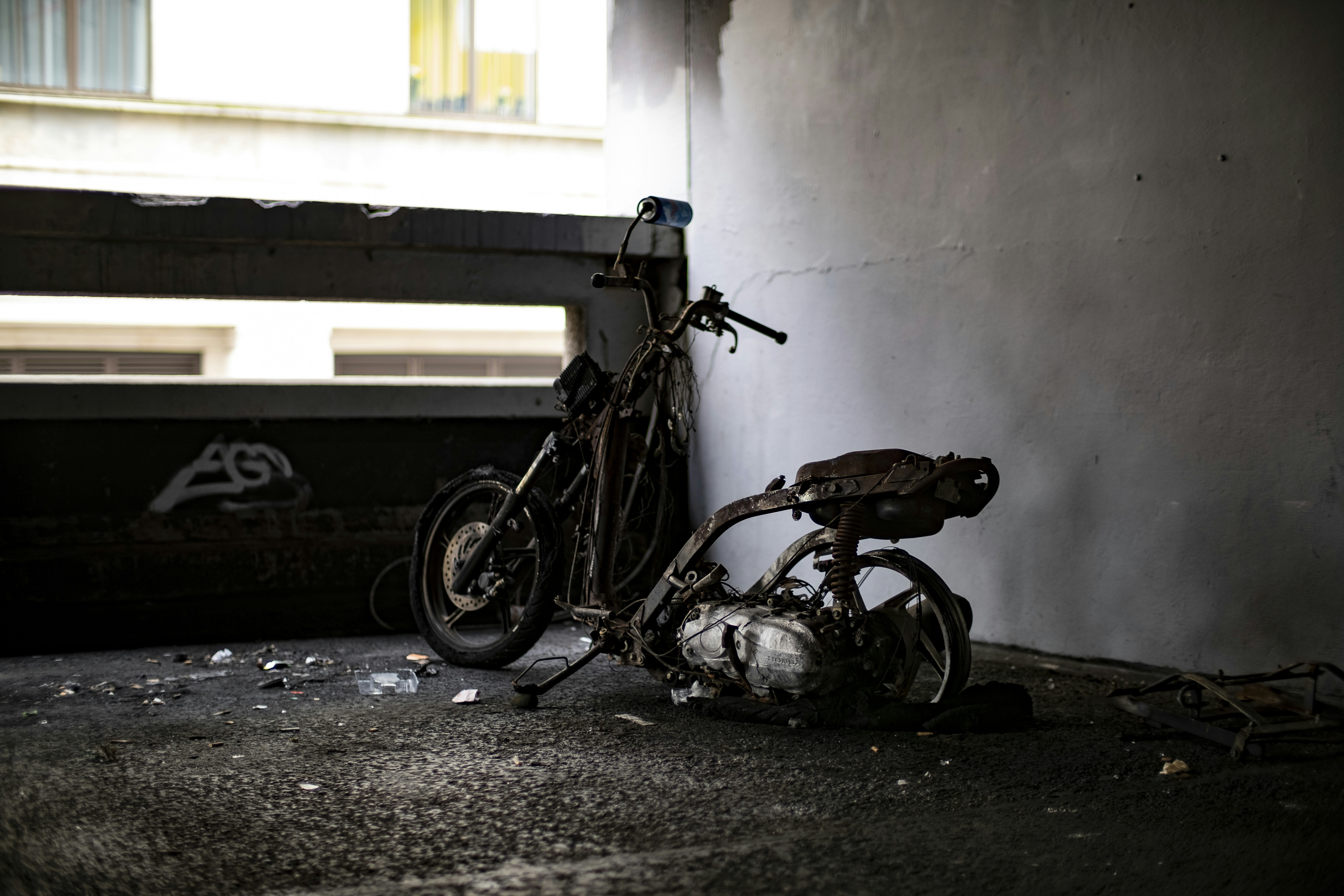 broken down motor scooter beside white wall, 