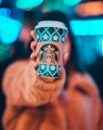 woman on brown jacket showing green and brown Starbucks coffee cup