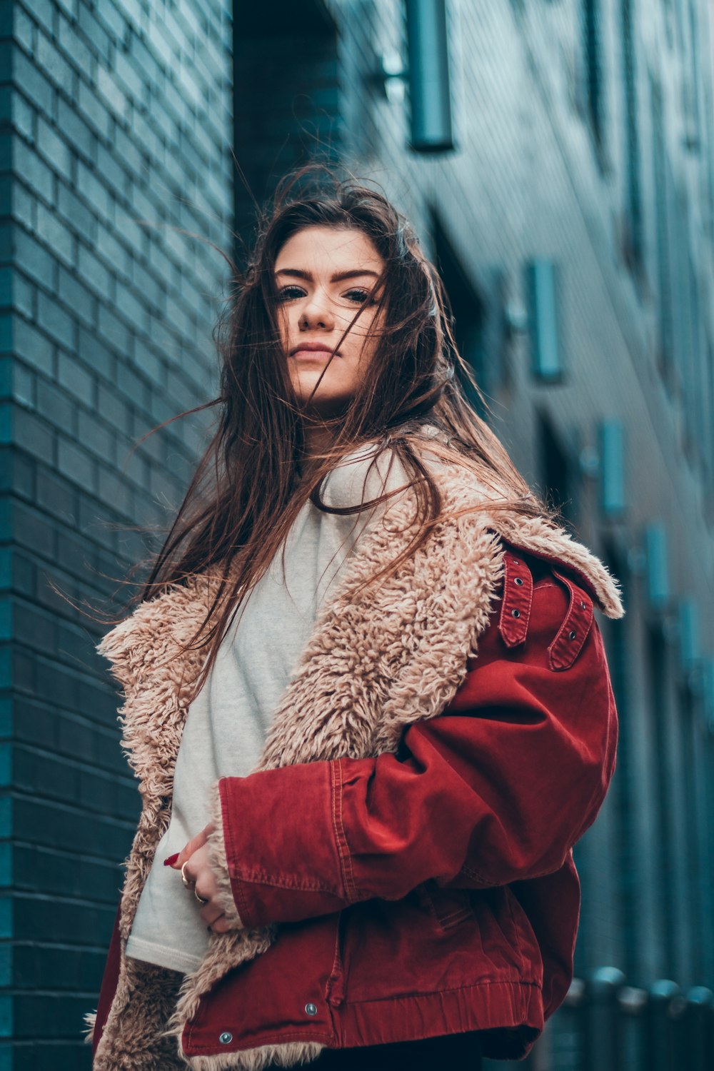 woman in red coat standing beside building on selective focus photography