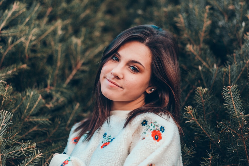 smiling woman between green pine trees