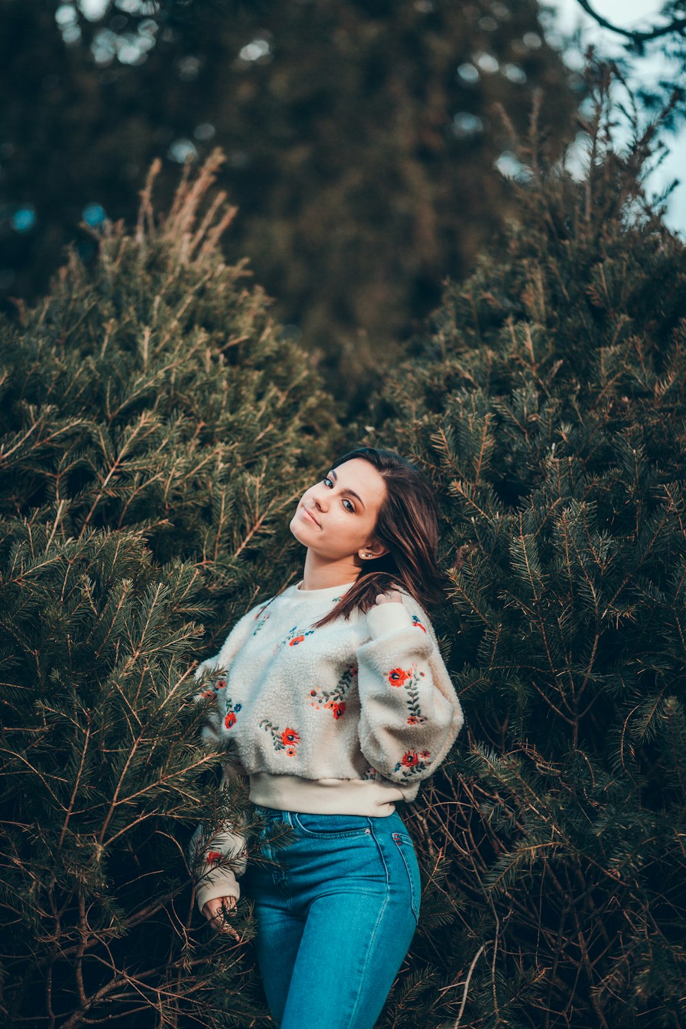 selective focus photography of standing woman surrounded by green trees during daytime