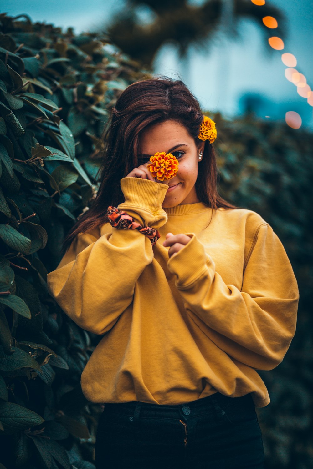 woman holding marigold flower by her face