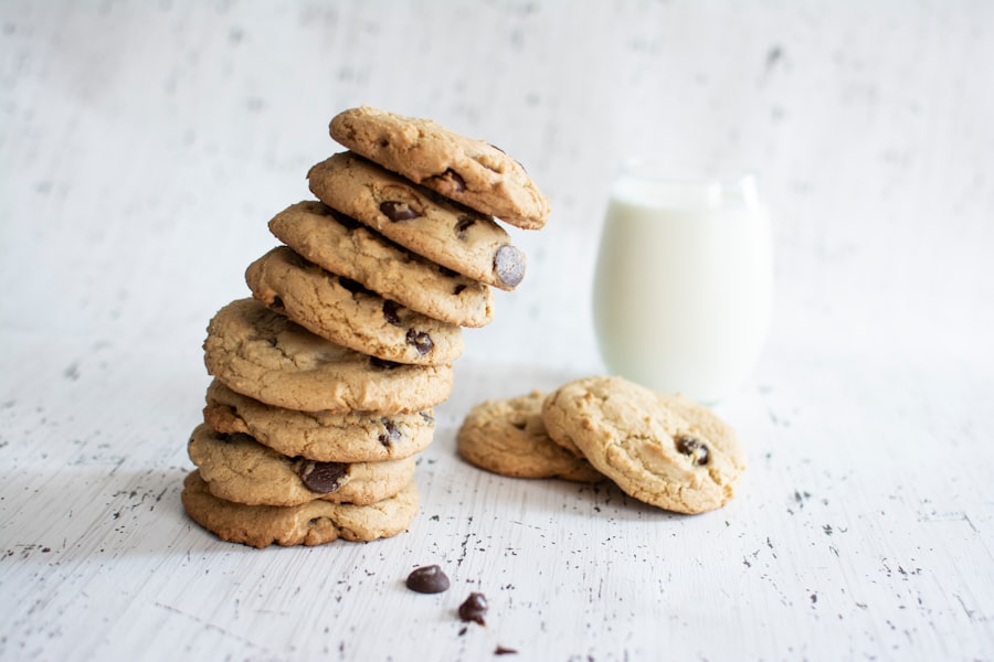 A stack of chocolate-chip cookies, with a glass of milk in the background.