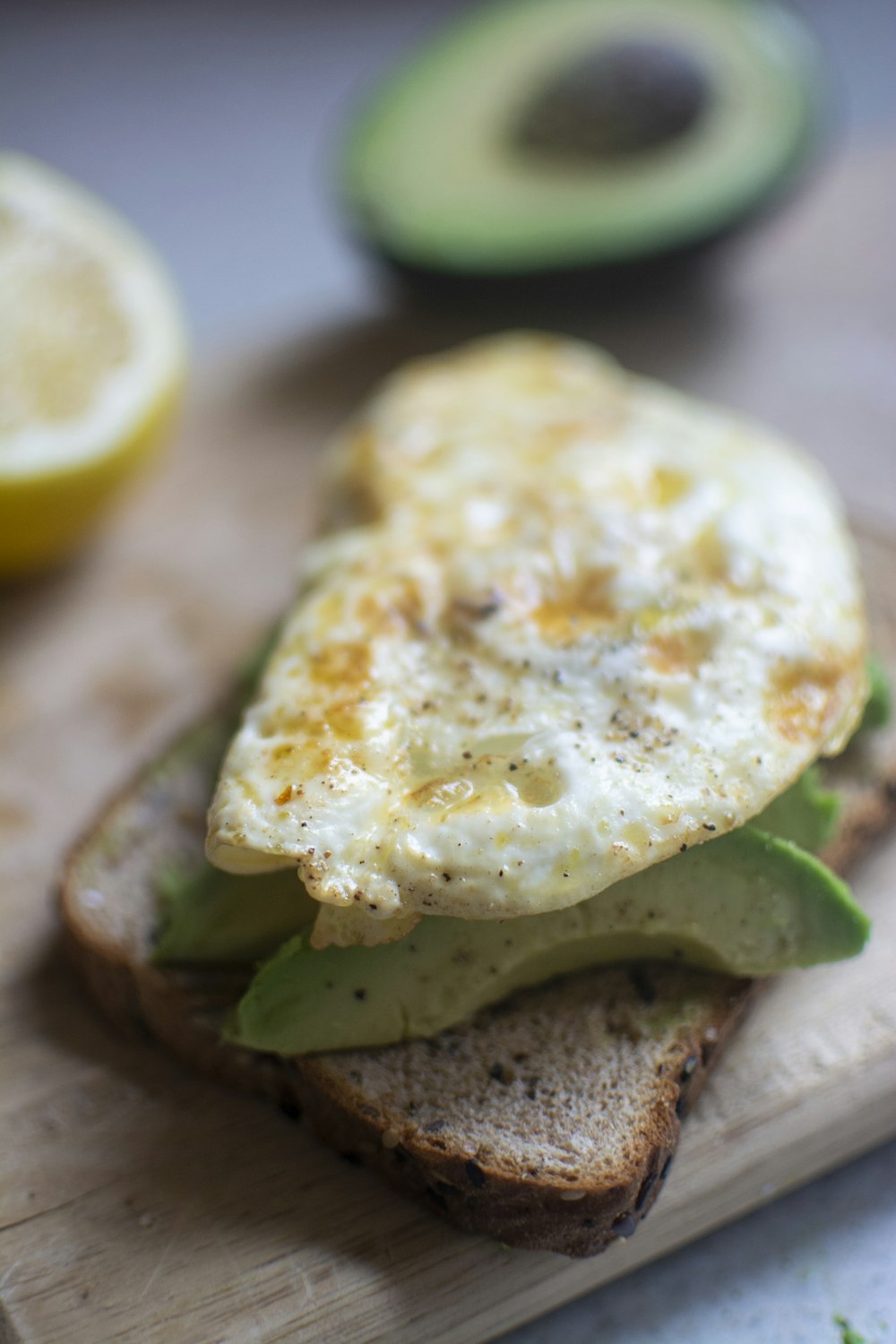 egg on top of avocado and bread on chopping board