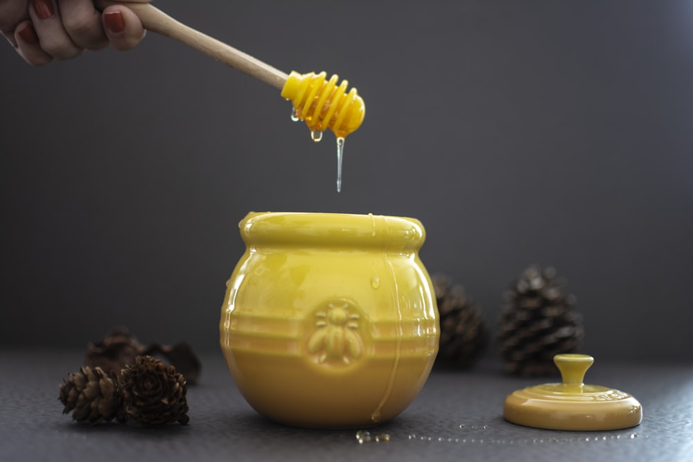 opened yellow ceramic jar beside pine cones