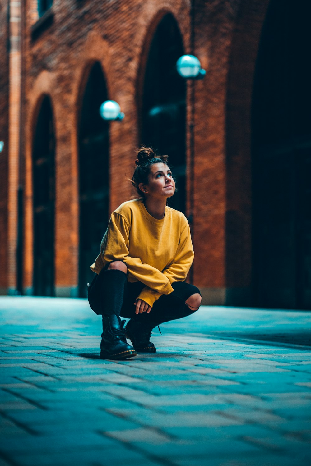 a woman sitting on the ground in front of a brick building