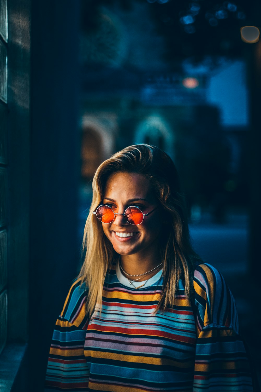 smiling woman wearing yellow, blue, and white stripe crew-neck t-shirt