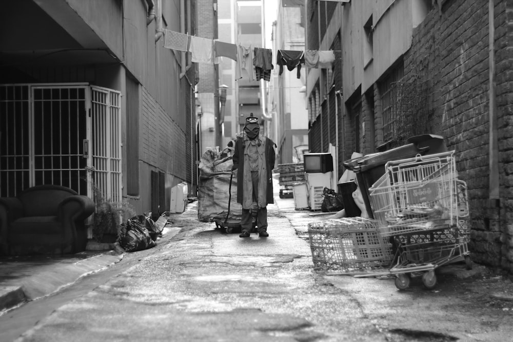 grayscale photography of man pulling cart in the middle of road