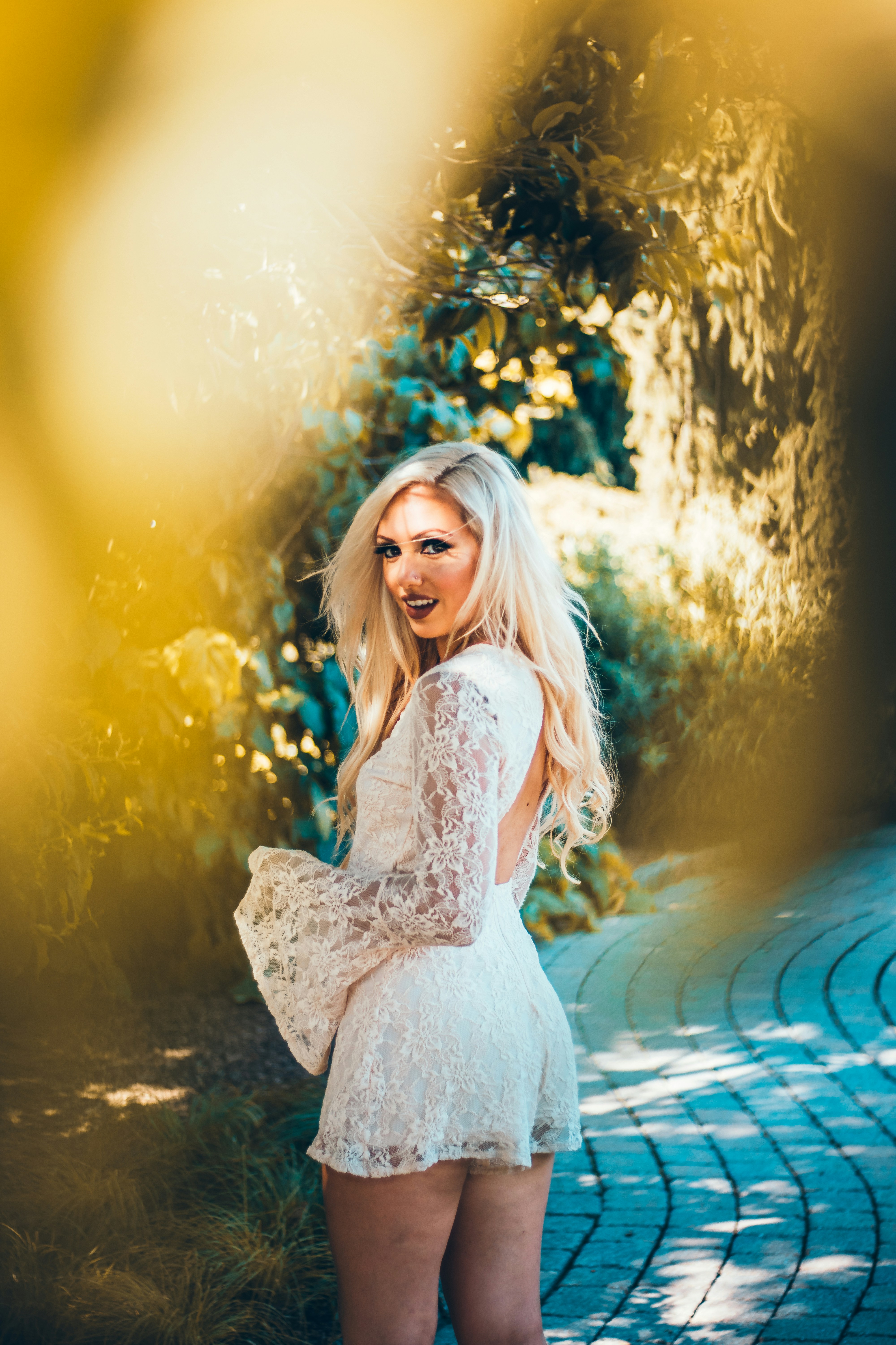 woman in white lace dress standing near plants