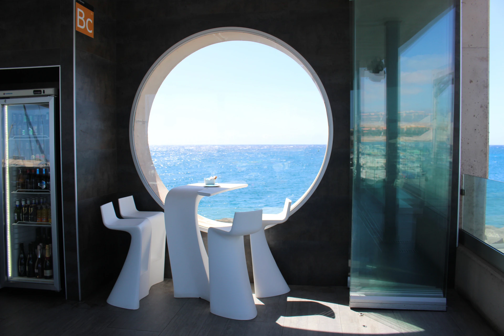 Sunlit modern interior of a villa showcasing spotless floors and large windows overlooking the sea.