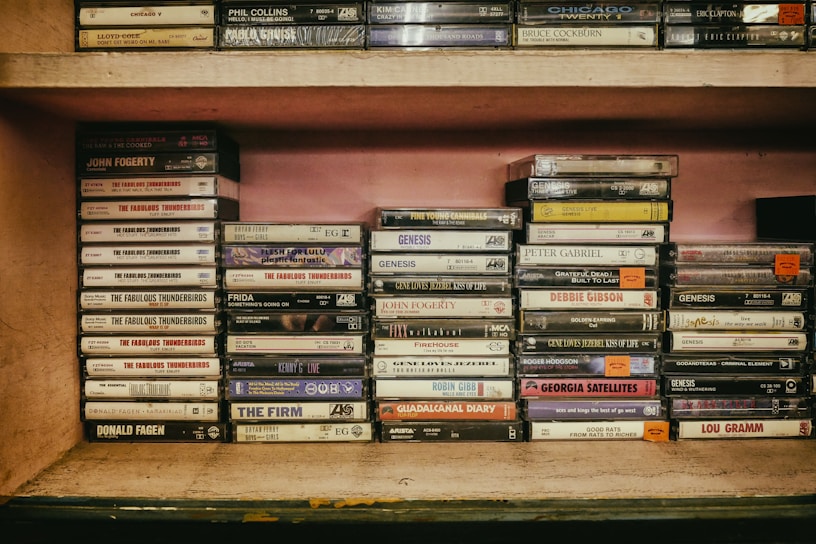 A collection of vintage audio cassette tapes displayed on a wooden shelf.