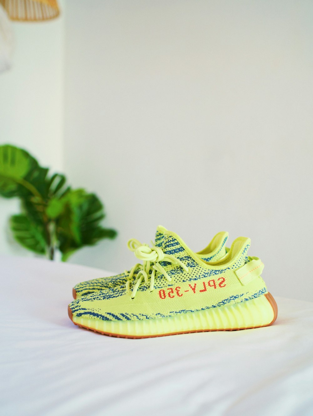 frozen yellow Adidas Yeezy Boost v2's on white bedspread