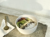 An inviting bowl of creamy chia pudding topped with sliced kiwi and a drizzle of honey.