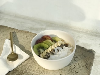 An inviting bowl of creamy chia pudding topped with sliced kiwi and a drizzle of honey.