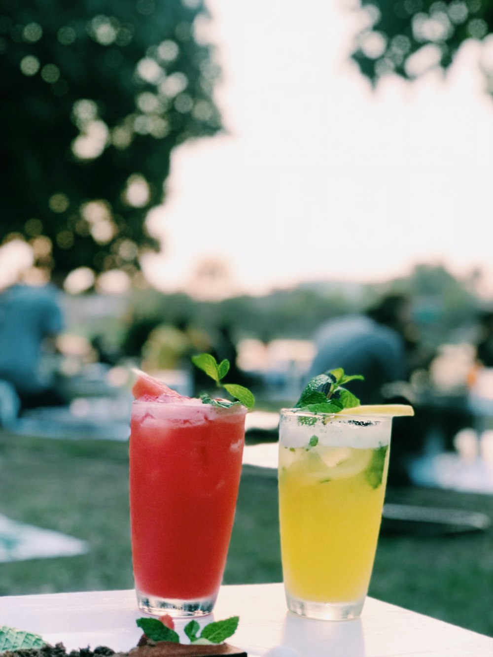 two clear drinking glass with red and yellow liquid inside