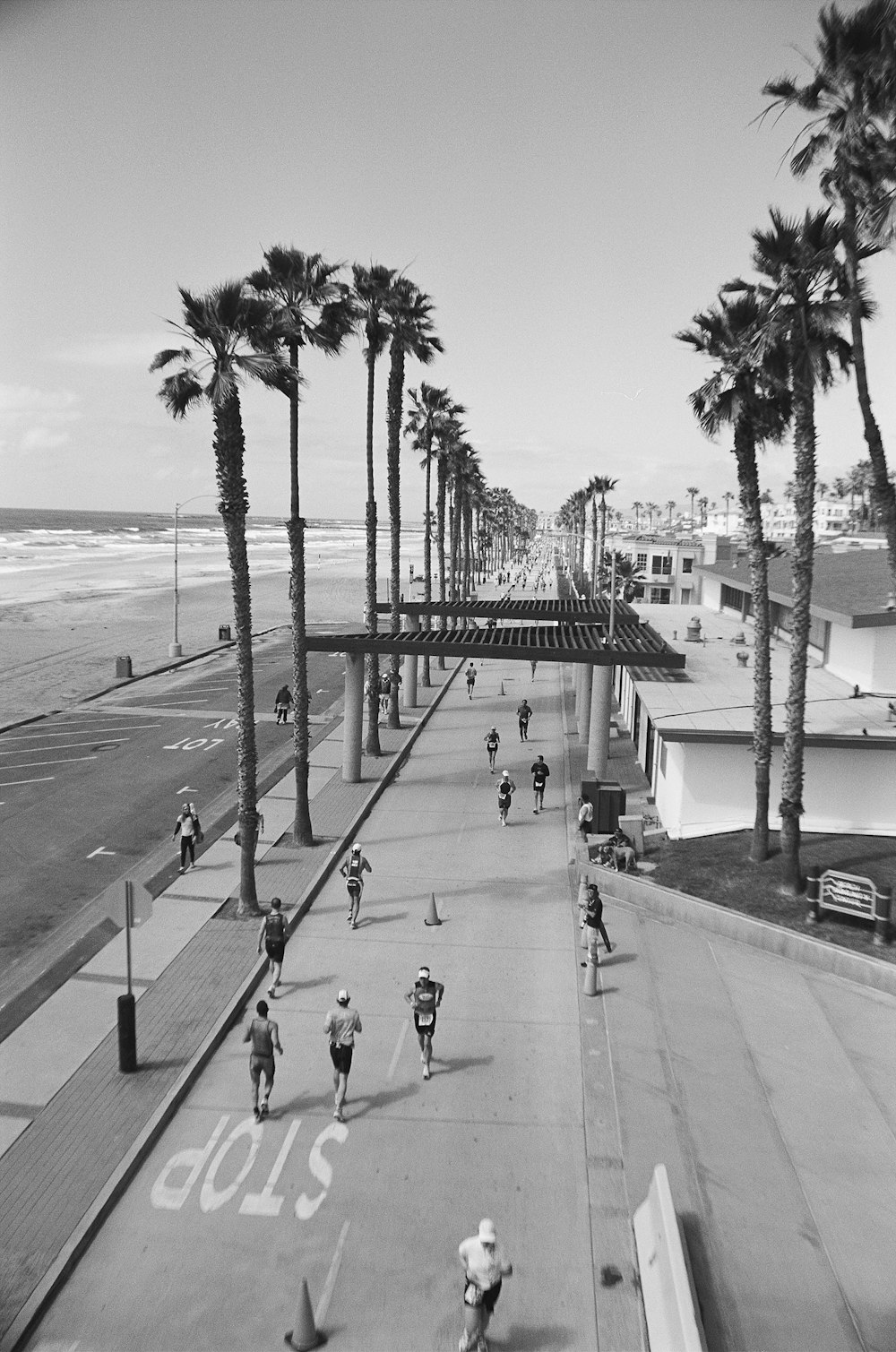grayscale photo of people running near body of water