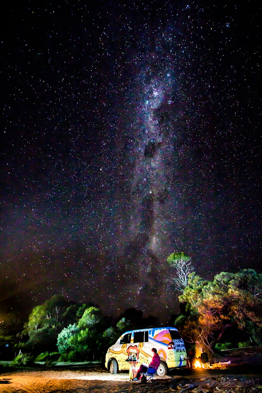 yellow van beside man sitting under starry sky