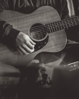 greyscale photography of person playing acoustic guitar