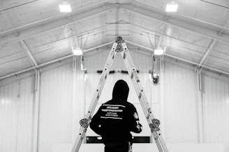low saturation photography of person in black hooding standing infront of ladder