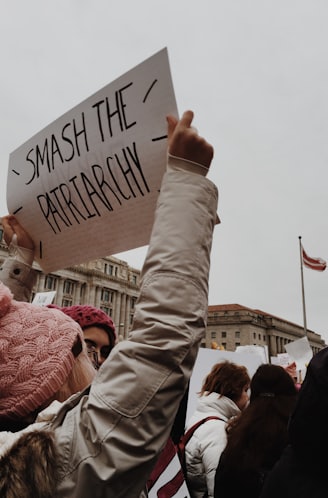 woman holding white paper with smash the patriarchy