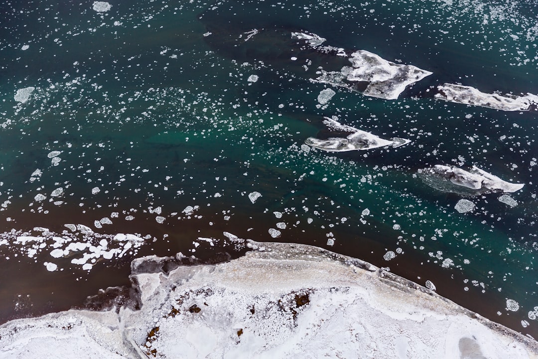 ocean beside mountain covered by snow