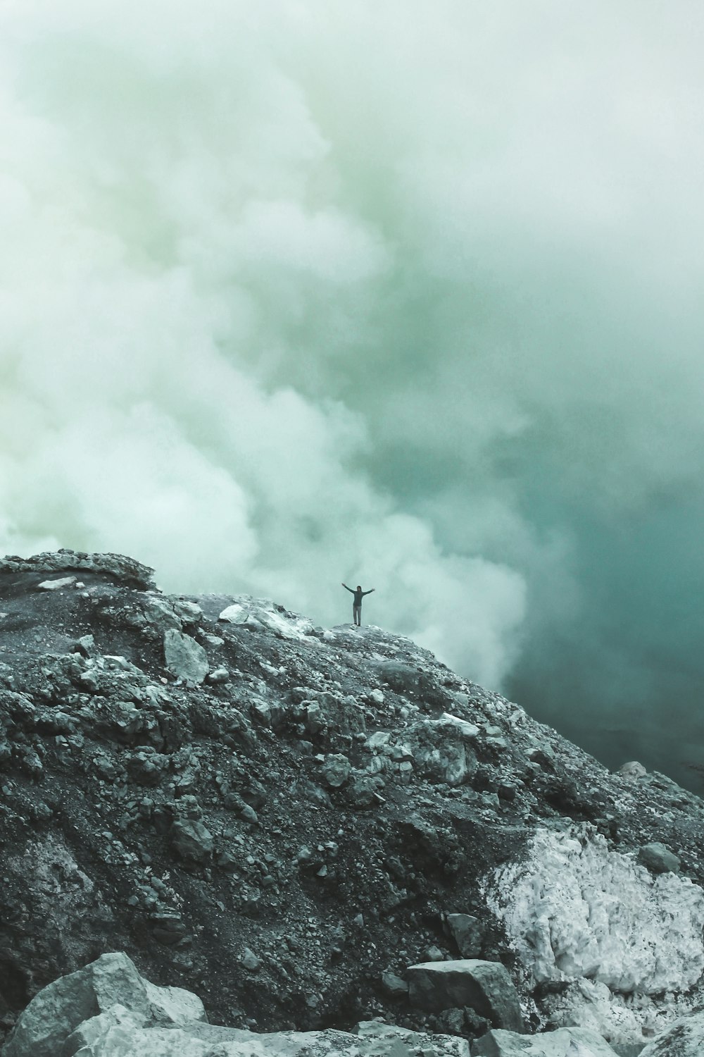 person standing on cliff with clouds background