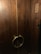 A set of large wooden double doors with a dark brown finish, featuring circular metal handles. There is a wooden plaque with Korean characters on the right side.