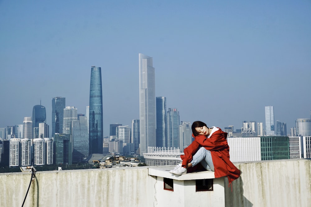 woman sitting on white concrete surface during daytime