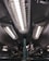 A series of industrial fluorescent lights are encased in protective grids, mounted on a dark ceiling with visible pipes and mechanical components.