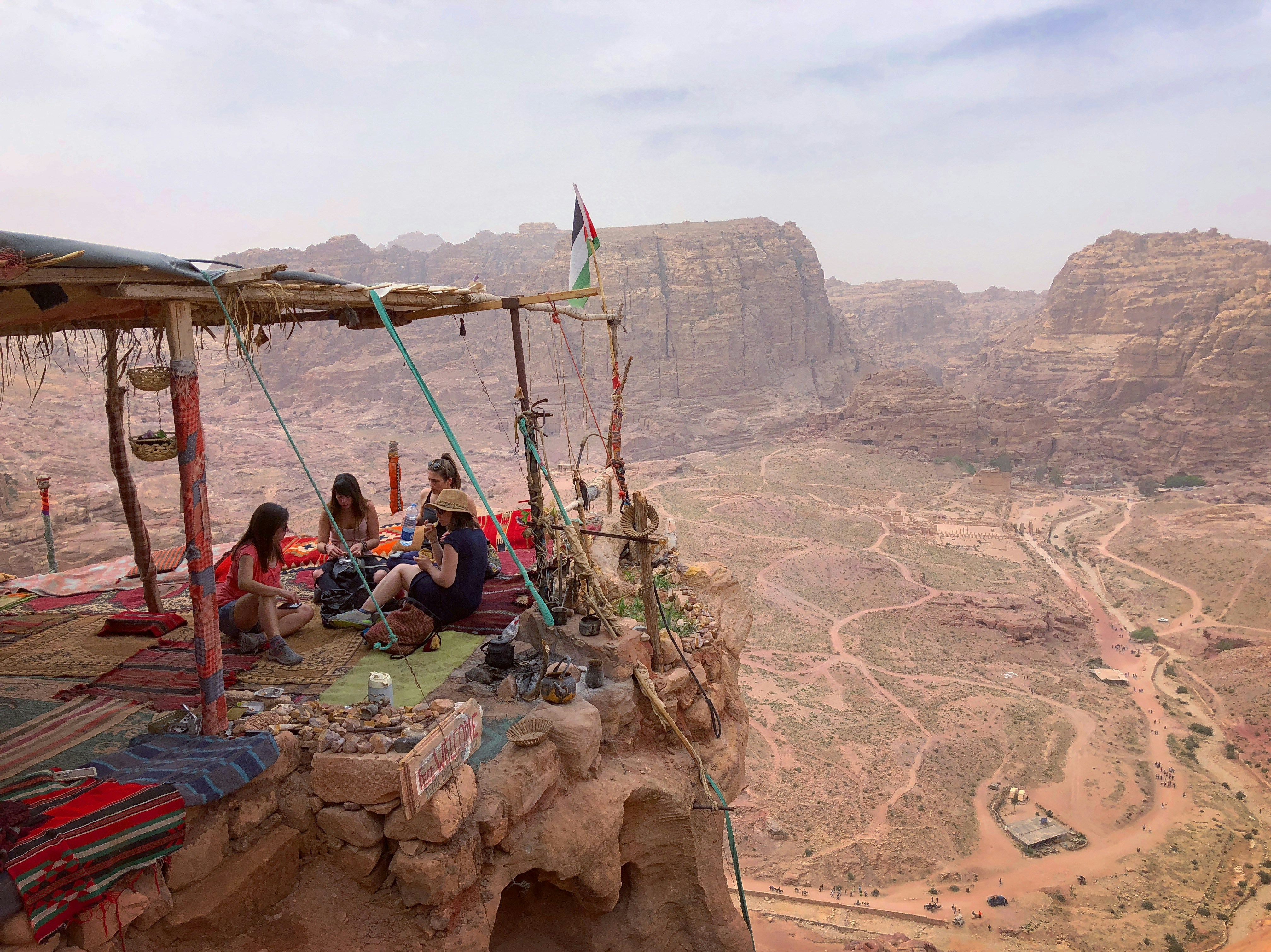 four person sitting on mountain hill during daytime jordan teams background